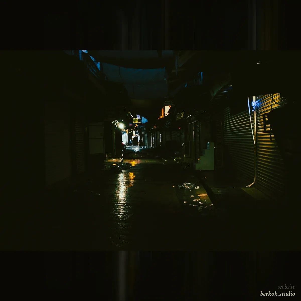 A dark covered market alley after rain